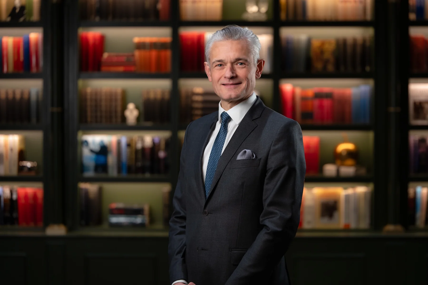 Distinguished executive in a tailored suit, photographed in a library